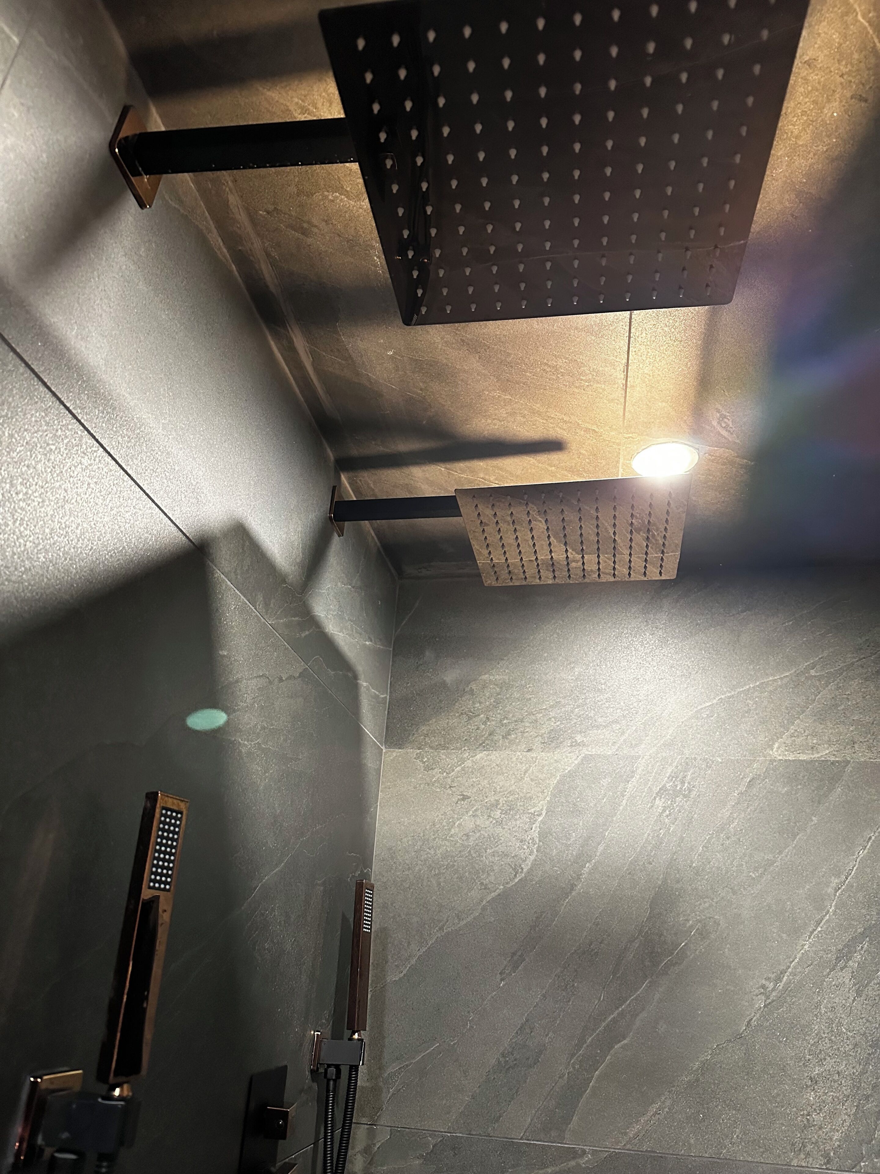 A modern bathroom with a shower, a towel rack, and a wall-mounted light fixture.
