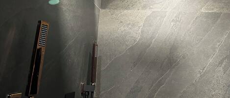 A modern bathroom with a shower, a towel rack, and a wall-mounted light fixture.