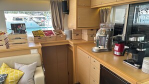 Une cuisine de taille réduite, dotée de meubles en bois, d’une machine à café et d’un réfrigérateur.