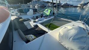 Un pont de bateau doté d’un espace salon couvert, d’une petite pelouse et d’un coussin blanc.