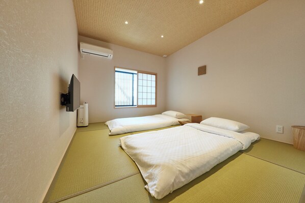 A room with two beds, a TV, and a window.