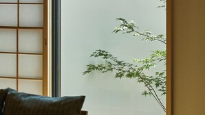 A room with a wooden floor, a cushioned bench, and a large window with a view of greenery outside. - KawaKawa 2-minute walk from Kiyomizu Gojo Station, Kyoto, near Kiyomizu Temple and Kamo River, accommodates up to 6 people, luggage storage available, modern Japanese-style villa, close to famous sightseeing spots, travel with family and friends (京都市東山区問屋町通五条下る三丁目東橘町)