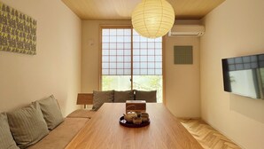 A modern living room with a wooden dining table, a sofa, and a large window with a view. - KawaKawa 2-minute walk from Kiyomizu Gojo Station, Kyoto, near Kiyomizu Temple and Kamo River, accommodates up to 6 people, luggage storage available, modern Japanese-style villa, close to famous sightseeing spots, travel with family and friends (京都市東山区問屋町通五条下る三丁目東橘町)