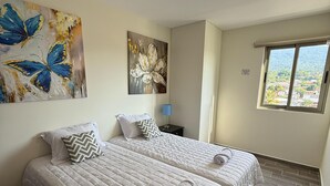 Een hotelkamer met twee bedden, een groot raam en kunst aan de wanden.