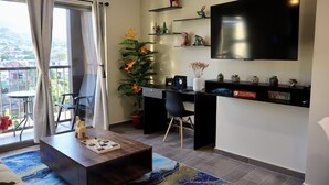 Een moderne woonkamer met een grote televisie, een bureau en een balkon met uitzicht.