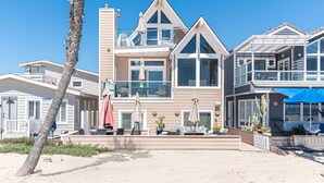 Una propiedad frente a la playa con varios niveles, mobiliario exterior y una zona de piscina.