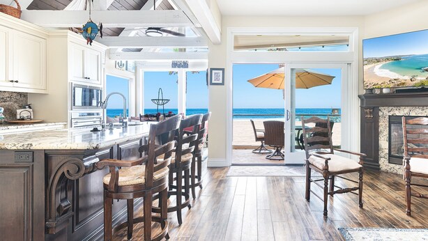 Una cocina con una isla grande, taburetes de bar y vistas al océano a través de un ventanal.