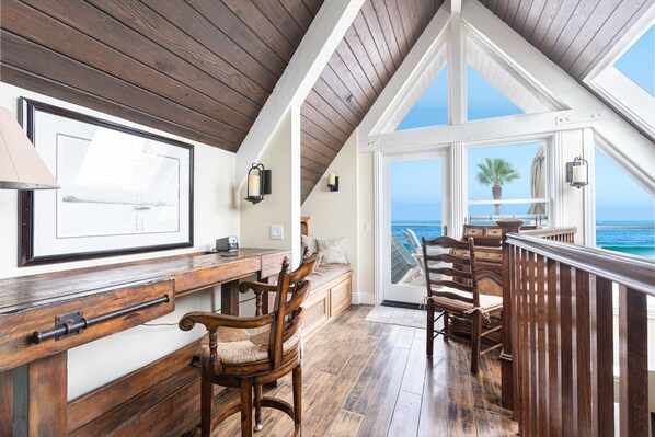 A high-ceilinged room with a wooden ceiling and a large window overlooking the ocean.
