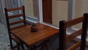 A wooden dining table with four chairs, a potted plant, and a tiled floor. - Hostal De María (San Cristóbal de las Casas)