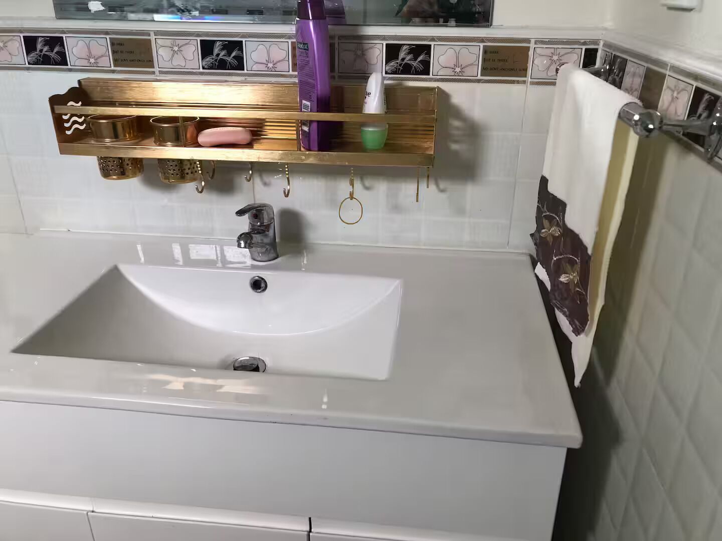 Ein Badezimmer mit einem weißen Waschbecken, einer goldenen Kommode und einem Spiegel darüber.
