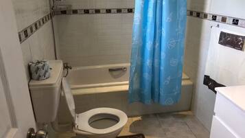 A bathroom with a toilet, bathtub, and shower curtain.