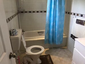 A bathroom with a toilet, bathtub, and shower curtain.