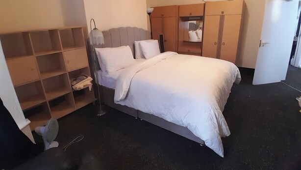 A hotel room with a bed, a wardrobe, a mirror, and a fan. - Modern Seaside Stay at Bela Grove-Sleeps8 (Blackpool)