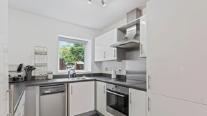 A modern kitchen with white cabinets, a Bosch dishwasher, a stainless steel oven, and a window providing natural light.