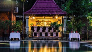 A restaurant with a purple roof, outdoor seating, and a pool in the foreground. - De Arya Angkor Resort (Siem Reap)