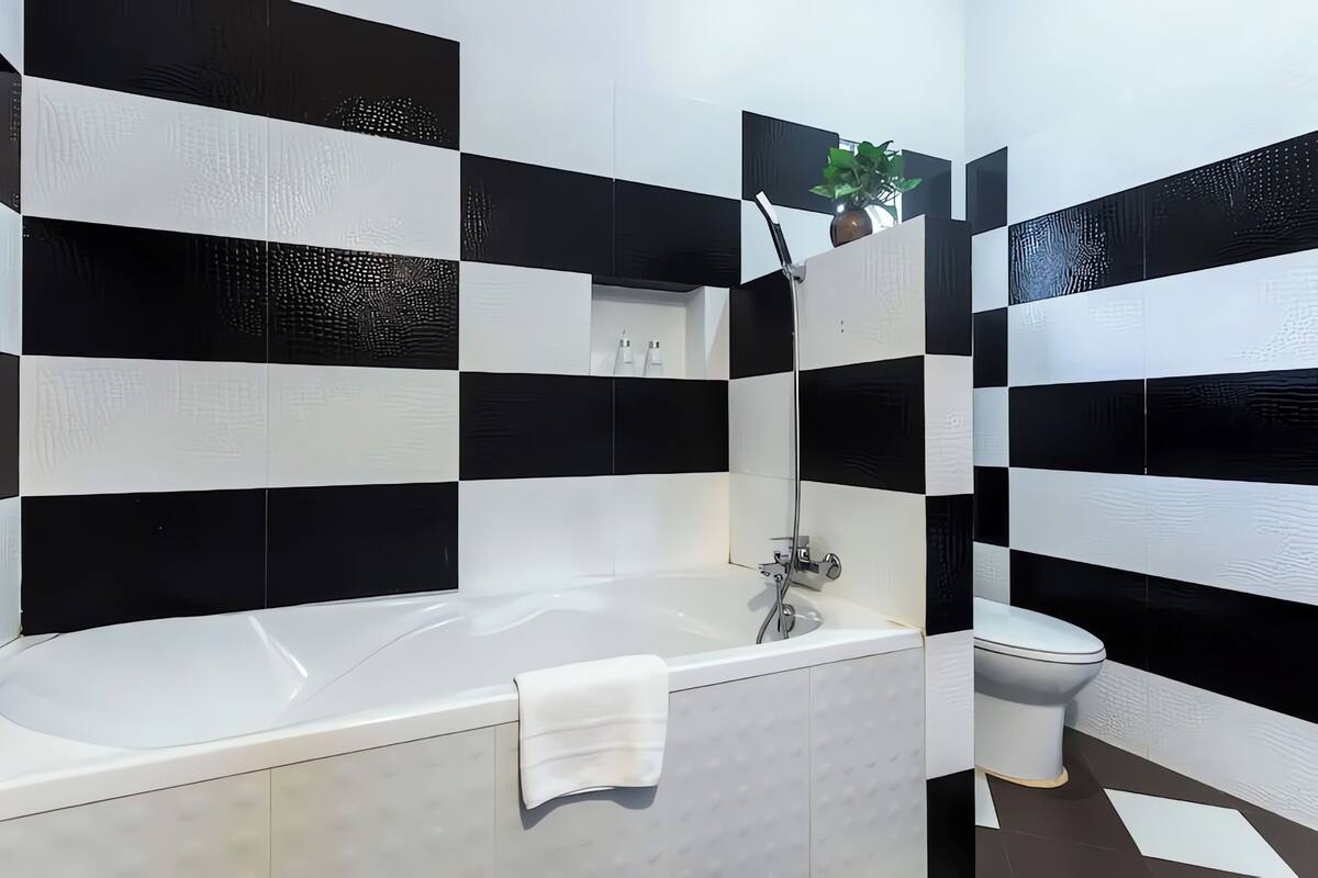 A bathroom with a black and white checkered tile pattern, a white bathtub, and a white toilet.
