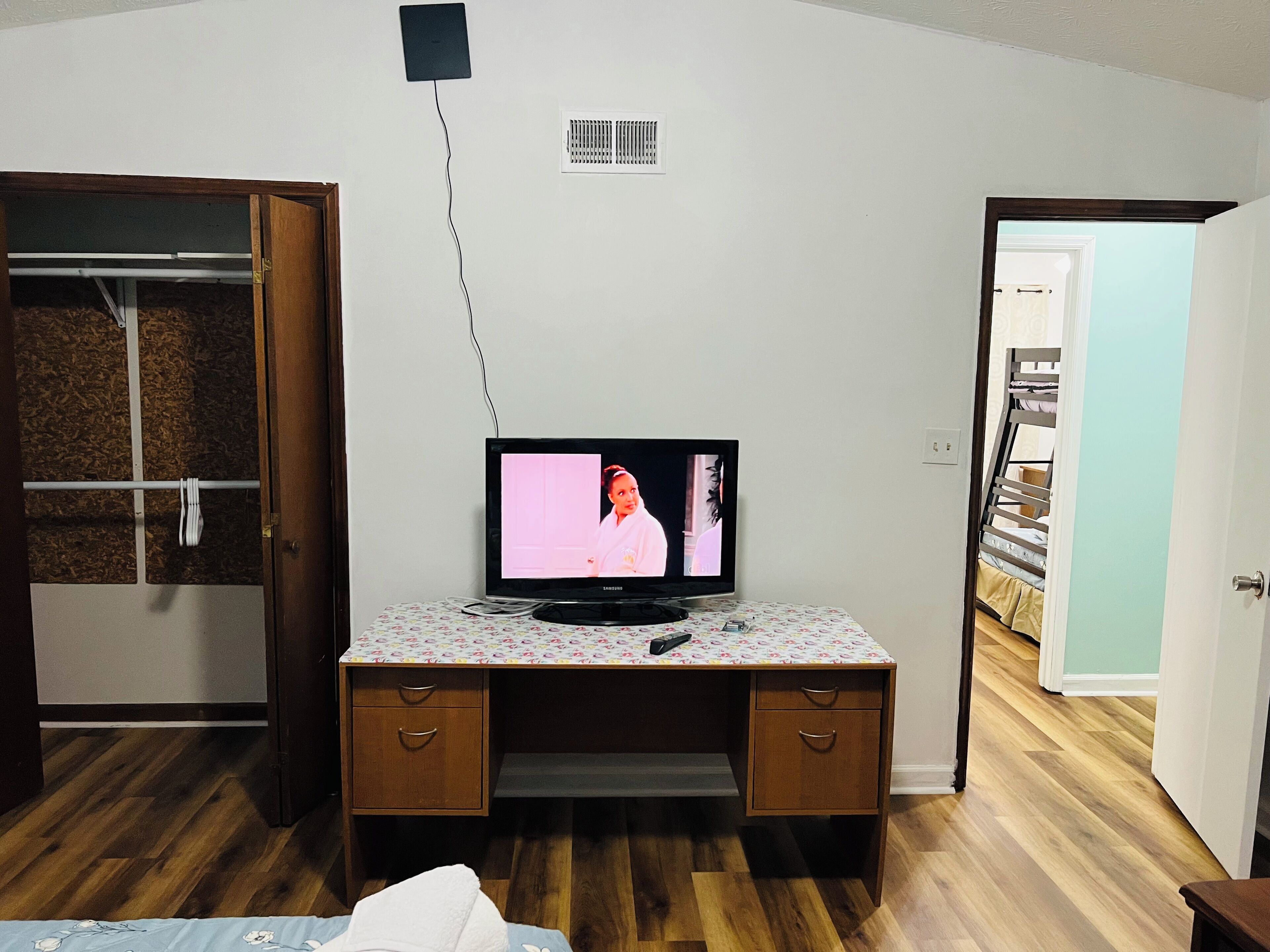 A bedroom with a wooden desk, a television, and a bed.