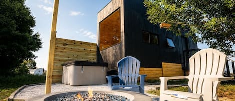 A modern outdoor seating area with a fire pit, two Adirondack chairs, and a wooden deck.