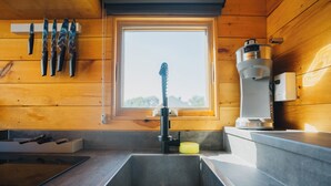 Une cuisine équipée d’un évier, d’une fenêtre et d’une machine à café.