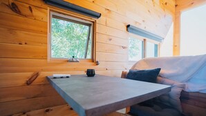 L’intérieur d’un chalet en bois, avec une table, un canapé et une fenêtre.