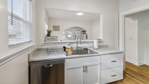 A modern kitchen with white cabinetry, a stainless steel sink, and a dishwasher. - Pet-Friendly 1BR Duplex Near Butler University ~ Sleeps 2 ~ Fast Wi-Fi (Indianapolis)