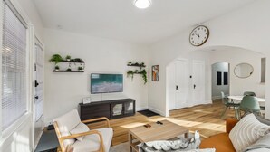 A modern living room with a sofa, coffee table, TV, and decorative plants. - Pet-Friendly 1BR Duplex Near Butler University ~ Sleeps 2 ~ Fast Wi-Fi (Indianapolis)