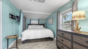 Een slaapkamer met een bed, een dressoir, een bureau en een raam met uitzicht.