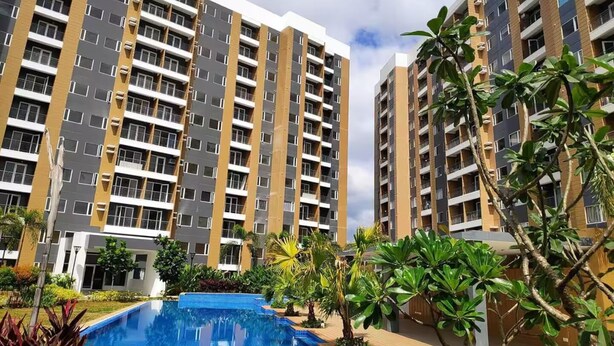 A modern apartment building with a swimming pool in the foreground.