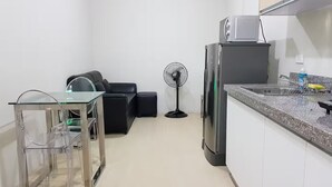 A compact kitchen with a refrigerator, a sink, and a dining area with a glass table and chairs.
