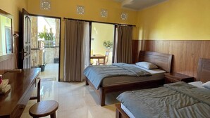 A hotel room with two beds, a desk, and a chair. There is a view of the outside through the door. - Casa de cavin (Ubud)