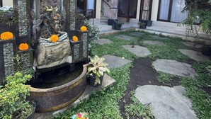 A courtyard with a fountain, stone steps, and potted plants. - Casa de cavin (Ubud)