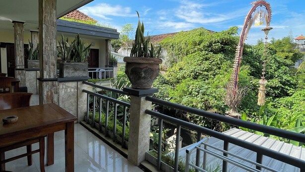 A balcony with a view of lush greenery and a decorative archway. - Casa de cavin (Ubud)
