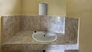 A bathroom with a marble sink, a mirror, and an air conditioning unit above. - Casa de cavin (Ubud)