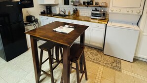 A compact kitchen with a wooden table, white cabinets, a black refrigerator, a white stove, and a microwave. - Fantastic apartment with AC in charming downtown Leesburg (Leesburg)
