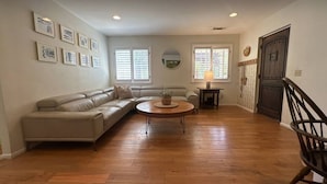 Una sala de estar con un sofá seccional color beige, una mesa de centro redonda y piso de madera.