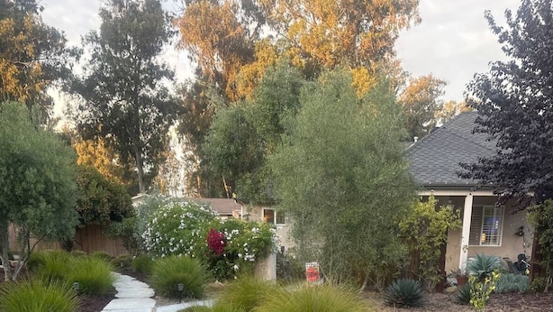 Un sendero en un jardín que lleva a una casa con techo inclinado y un garaje visible.