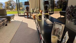 Un salon moderne doté d’une grande fenêtre offrant une vue panoramique sur les arbres et les montagnes.