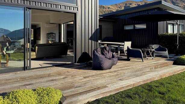 Une maison moderne dotée d’une grande porte-fenêtre coulissante qui donne sur un espace de vie comprenant un canapé et une table à manger.