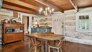 A rustic kitchen with wooden cabinets, a wooden dining table, and a chandelier.