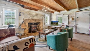 A rustic living room with a stone fireplace, wooden ceiling beams, and a television.