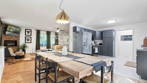 Een moderne keuken met grijze kastjes, een houten eettafel en een hangende吊灯