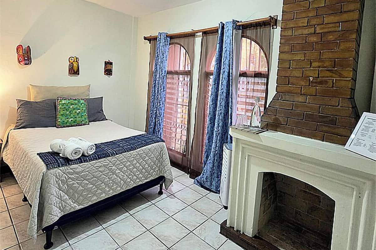 Une chambre à coucher avec un lit, une cheminée et une fenêtre avec des rideaux.