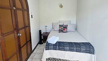 Un dormitorio con cama, mesita de noche, lámpara, armario y luz de techo.