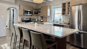 Una cocina moderna con una isla central, electrodomésticos de acero inoxidable y una lámpara colgante.