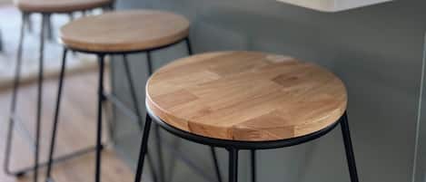 Una cocina moderna con una isla central, tres taburetes de madera y una planta en maceta.