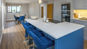 A modern kitchen with a large island, bar stools, and a dining area with a table and chairs.