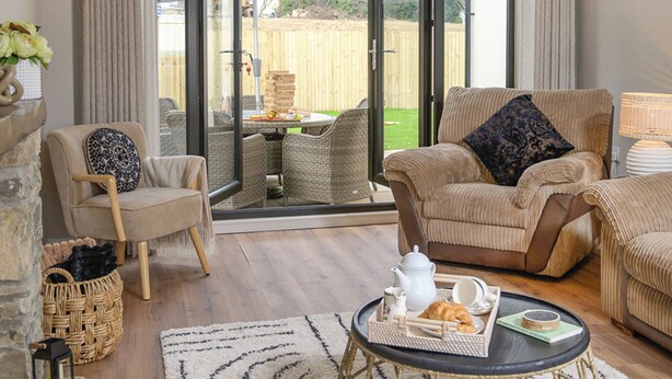 A cozy living room with a fireplace, a dining area with outdoor seating, and a large sliding glass door leading to a garden.