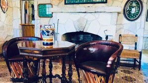 A room with a stone fireplace, a table with chairs, and a patterned rug. - 7 acres with rare private Medina River access! 5 minutes to downtown Bandera!  (Bandera)