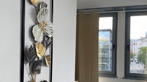 A modern living room with a large window, a blue sofa, and a decorative wall piece. - Modern & central in the cityI 8 guests I kitchen I washing machine I balcony (Stuttgart)