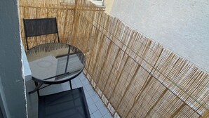 A small outdoor patio area with a round table and a rectangular table, surrounded by a bamboo fence. - Modern & central in the cityI 8 guests I kitchen I washing machine I balcony (Stuttgart)